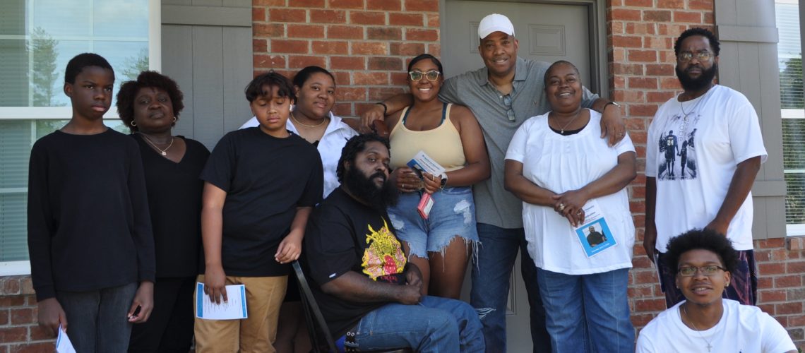 New homeowner Dontrel Washington (seated, center) is surrounded by friends and family during his dedication ceremony on Saturday, June 11.